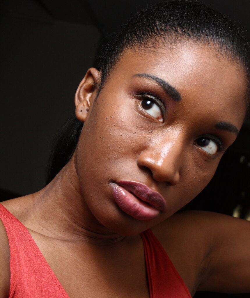 A woman wearing a red top gazes confidently at the camera.